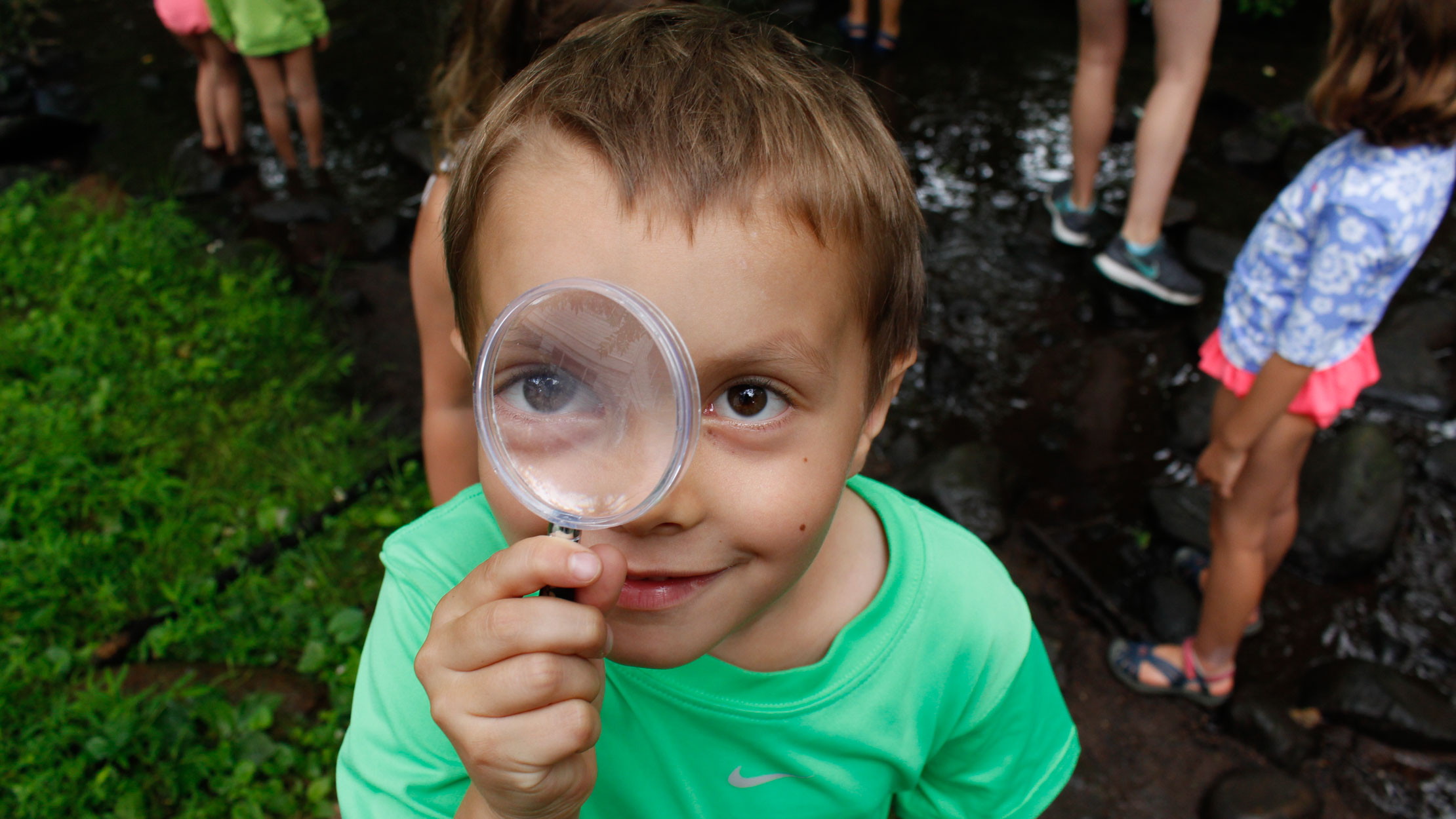 Young camper looking through a magnifying glass