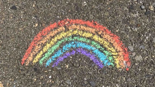 Drawing of a rainbow with chalk on pavement