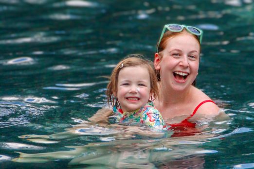 A counselor and camper in the pool smiling with water in the background