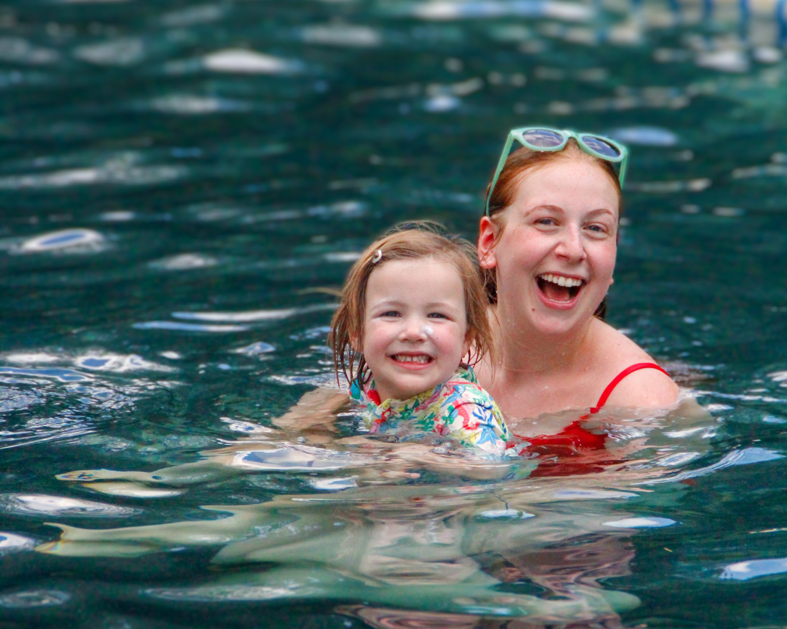 A counselor and camper in the pool smiling with water in the background