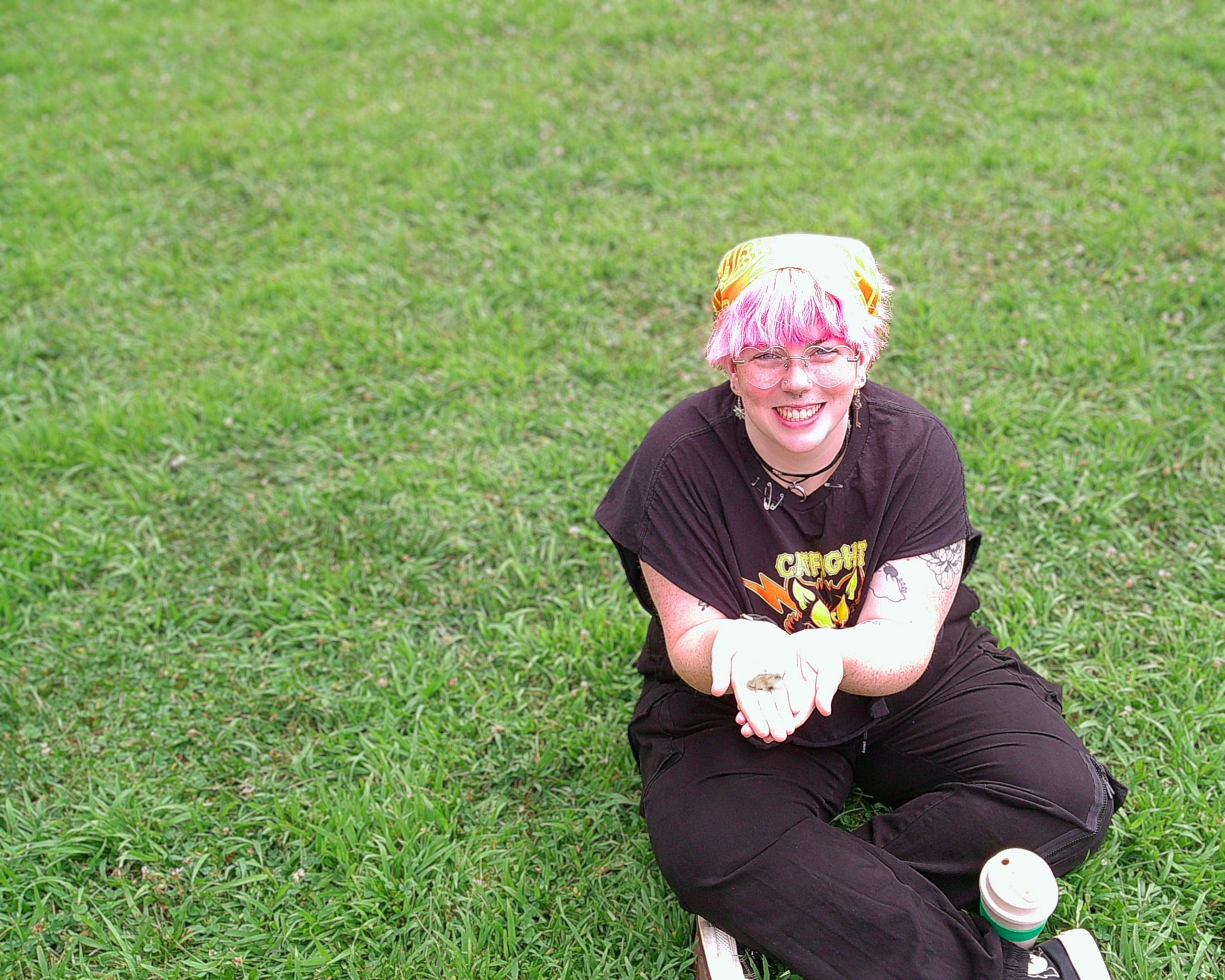 Camp counselor sitting on the grass holding a toad
